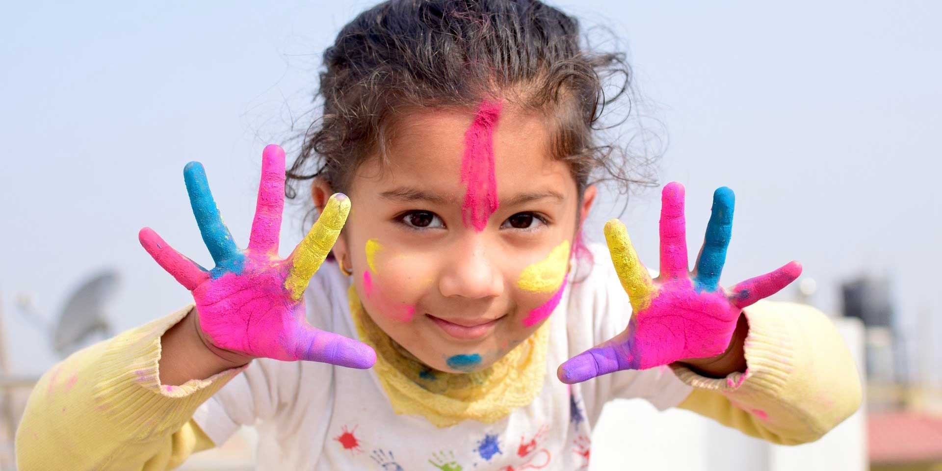 Niña mostrando sus manos pintadas de colores